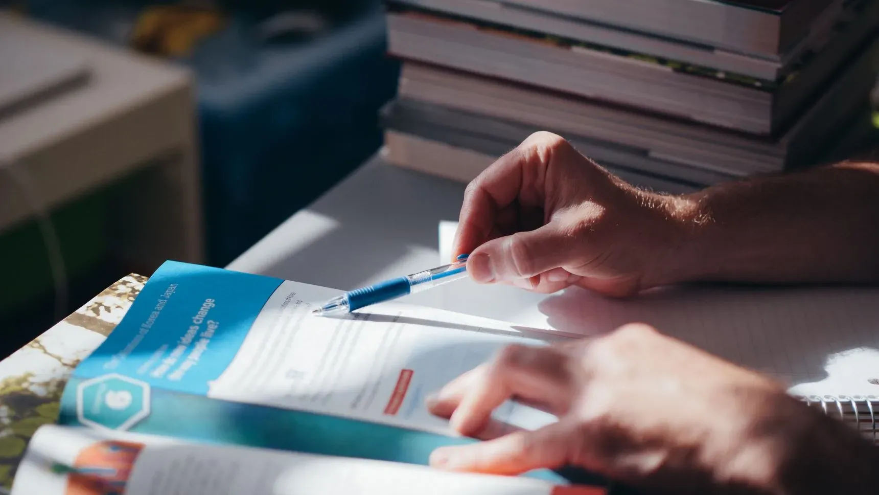 Hands working through documents with a pen at a desk