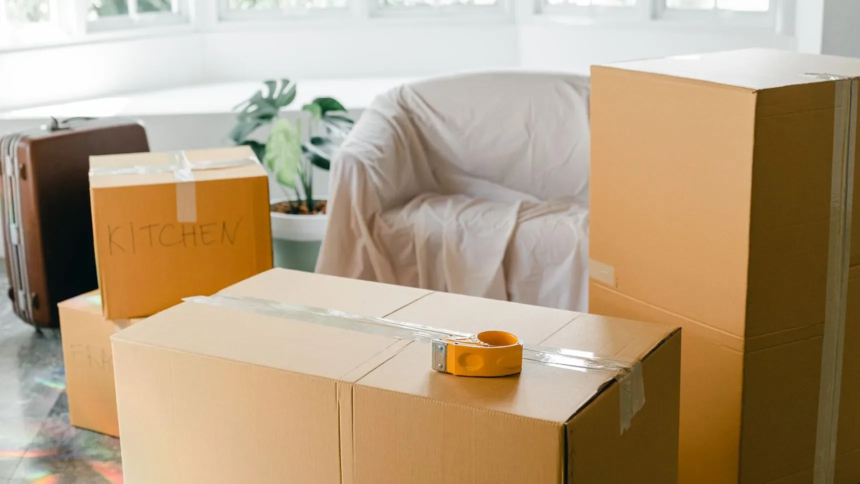 Moving boxes and a suitcase in a bright, empty room